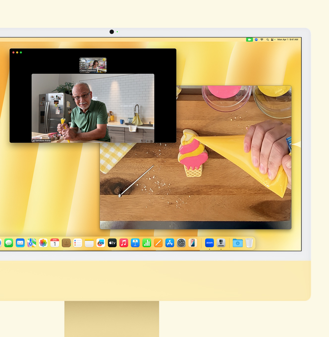 iMac amarillo. Demostración de Vista del Escritorio. La pantalla muestra una videollamada entre la repostera y otra persona. Una pantalla muestra los rostros de la repostera y el hombre, mientras que la otra muestra las manos de la repostera glaseando una galleta