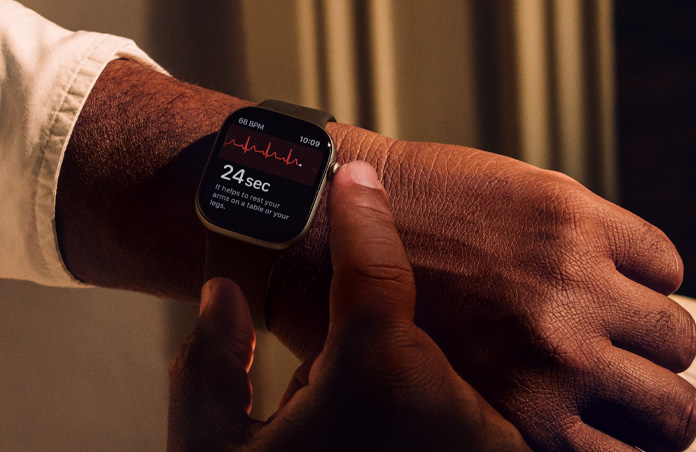 A person presses and holds the Digital Crown on Apple Watch Series 11 to measure heart health in ECG app