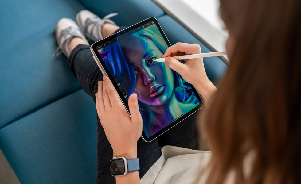 A student holding an iPad on her lap while using an Apple Pencil to draw in the Procreate app
