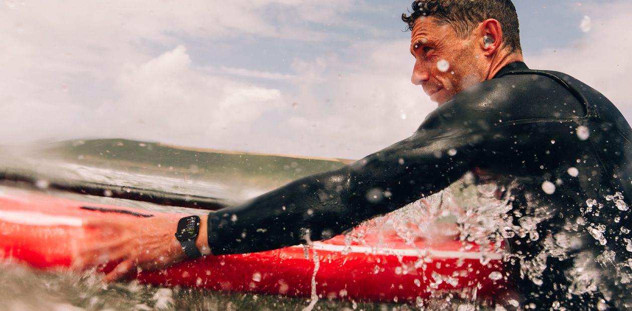 Un homme surfe avec une Apple Watch au poignet.