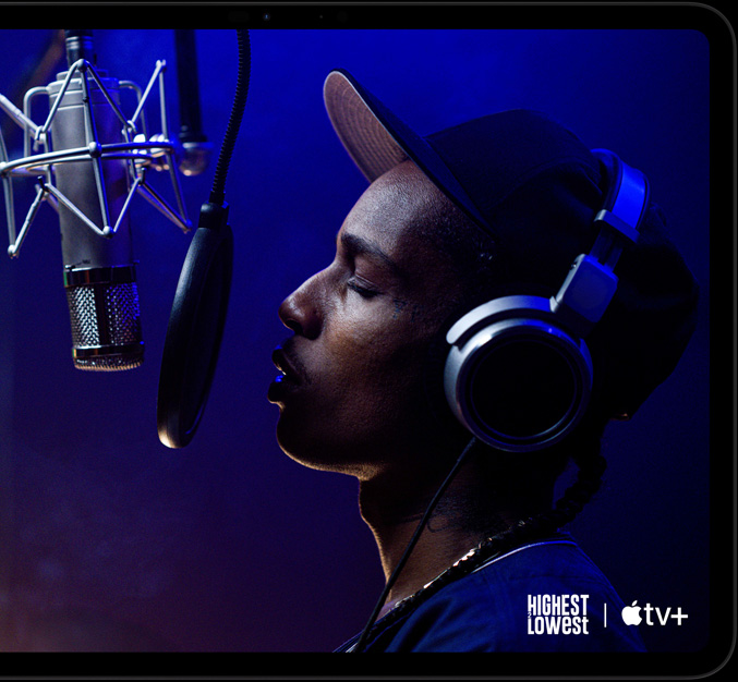 iPad Pro, vaakasuunnassa, etupuoli, tähtimusta väri, pyöristetyt kulmat, musta näytön kehys, näytöllä AppleTV+:lta toistetaan Apple TV+:n elokuvasta Highest 2 Lowest kohtausta, jossa ASAP Rocky esittää Yung Felonia ja räppää mikroniiin