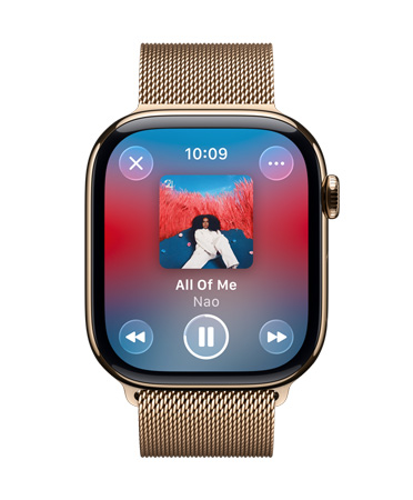 Apple Watch z tytanu w kolorze złotym z bransoletą mediolańską. Na tarczy widać odtwarzanie muzyki z Apple Music. Widoczne są też półprzezroczyste elementy sterujące Liquid Glass.